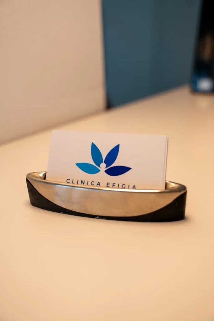 Cărți de vizită Clinica Efigia într-un suport metalic, pe biroul de la recepție