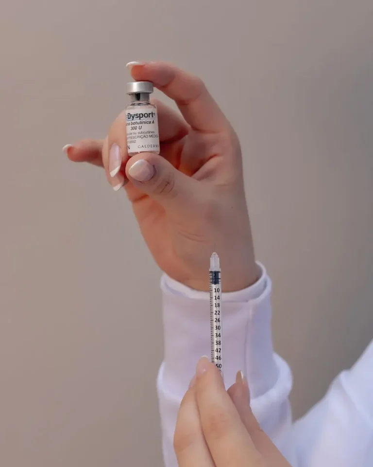 Mână care ține o seringă și o fiolă pentru un tratament injectabil