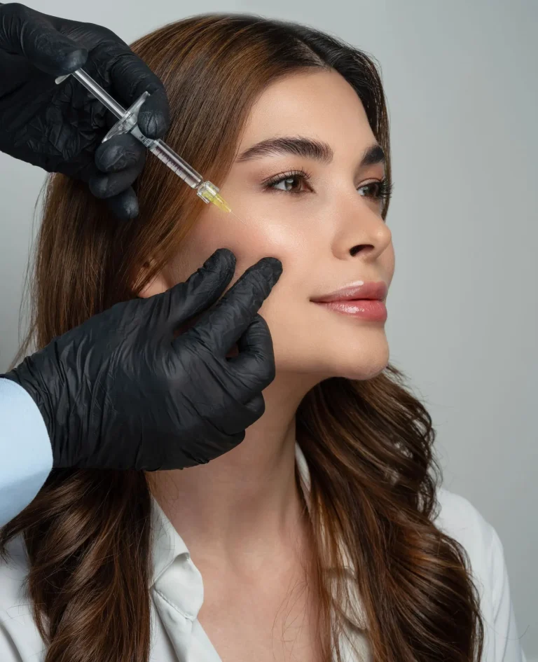 Medic cu mănuși care efectuează o injectare în zona pometului unei paciente